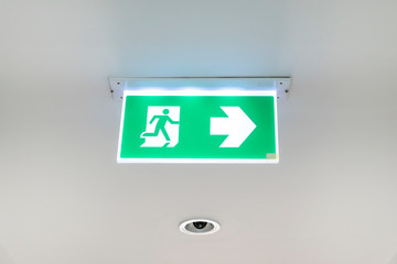 Fire exit sign. Emergency fire exit door exit door on ceiling. Green emergency exit sign showing the way.