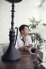 Fototapeta premium A young Asian businessman is waiting for a partner in a cafe. Business meeting in the restaurant. A Korean young man talking on the phone in a cafe.