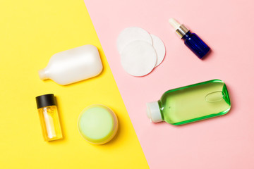Top view of cosmetic containers, sprays, jars and bottles on pink background. Close-up view with empty space for your design