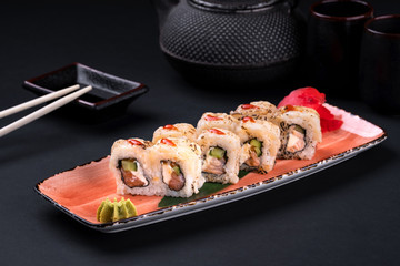 Close up rainbow Sushi Roll with salmon, eel, tuna, avocado, royal prawn, cream cheese Philadelphia, caviar tobica, chuka. Sushi menu. Japanese food and green tea teapot, copyspace.
