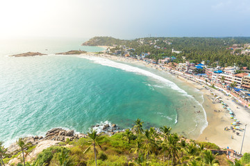 Aerial view of tourists taking a dip in the turquoise waters of Lighthouse beach at Kovalam,...