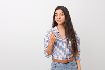 Young pretty arab woman pointing with finger at you as if inviting come closer.