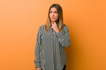 Young authentic charismatic real people woman against a wall looking sideways with doubtful and...