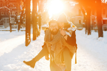 Portrait of handsomea lovely couple, hafing fun outside, in a winter day, sun lights background