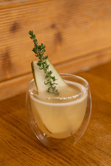 Hot fruit tea with pears and savory in transparent glass on wooden table. Cozy evening atmosphere