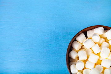 Marshmallow in a bowl on a blue  wooden background