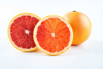 Fresh grapefruit and cut red flesh on white background