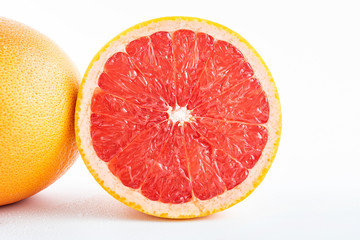 Fototapeta na wymiar Fresh grapefruit and cut red flesh on white background