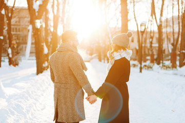 Photo of a couple walking, and holding hands, on a sun lights background
