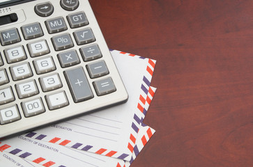 Calculator and mail envelopes on wooden table with copyspace. Count money for delivery letters...