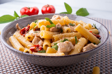 Pasta con carne di pollo e crema di formaggio, pomodorini e salvia