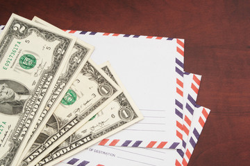 Sending mail cost concept, mail envelopes and money on wooden table.