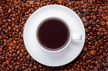 The cup of hot coffee with coffee beans