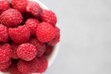 Ripe organic raspberries on gray background. Close-up. Soft focus.