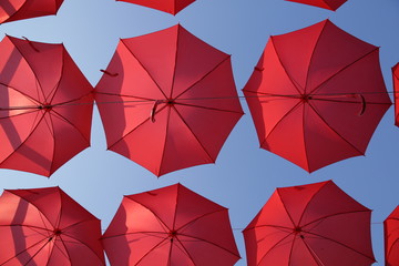 Red umbrellas against the blue sky. View from below. Abstract background with red umbrellas. Seamless pattern with umbrellas.