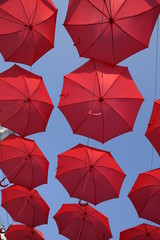 Red umbrellas against the blue sky. View from below. Abstract background with red umbrellas. Seamless pattern with umbrellas.