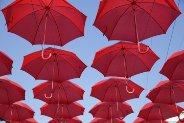 Red umbrellas against the blue sky. View from below. Abstract background with red umbrellas.