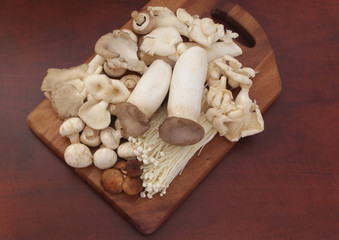 Assorted mushrooms on cutting board on brown table