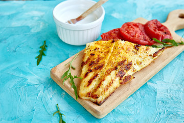 Grilled pike fillet with tomatoes on wooden board