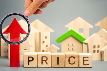 Wooden blocks with the word Price, up arrow and wooden houses. The increase in housing prices. Rising rent for an apartment. The growth of utilities. High house value. Real estate market