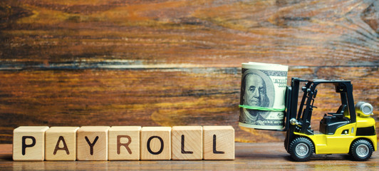 Wooden blocks with the word Payroll, money and a forklift. Payroll is the sum total of all...