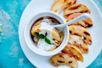 Grilled peach with ice creame on white plate