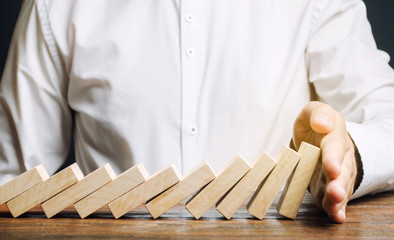 Businessman stops domino falling. Risk management concept. Successful strong business and problem...