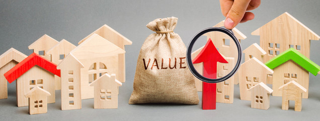 A money bag with the word Value, wooden houses and an up arrow. Concept of real estate market...