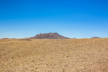 Fototapeta na wymiar minimalism landscape of desert sand stone valley foreground and lonely mountain ridge background 