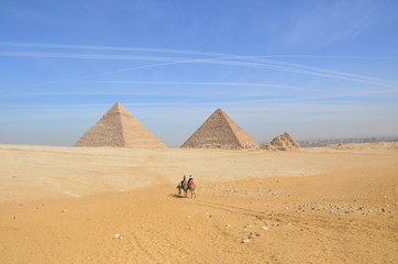 Egypt. Cairo - Giza. General view of pyramids from the Giza Plateau. Tourist riding camel crossing the desert.
