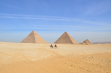 Fototapeta na wymiar Egypt. Cairo - Giza. General view of pyramids from the Giza Plateau. Tourist riding camel crossing the desert.