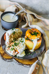 Baked bell peppers stuffed with sour cream. Minced rice, carrots in a plate on a wooden stand and a gray concrete background in a traditional rustic style with appliances