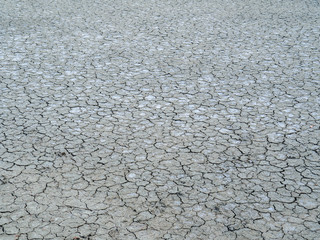 Dry earth covered with small cracks as drought and global warming concept. Cracked clay soil texture or ground pattern with cracks on surface top
