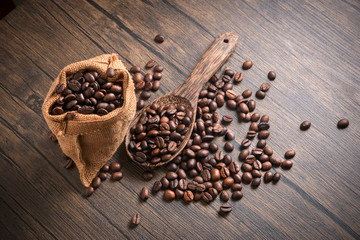 coffee beans in wooden spoon and sack bag of coffee on sack bag on wood background