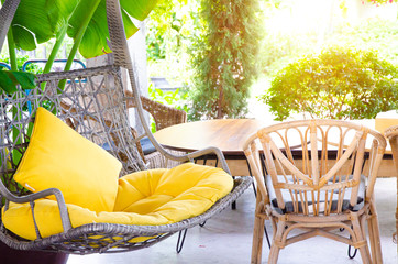 Rattan swings and yellow pillows in the morning garden.