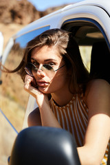 Beautiful girl in car, looking at camera in sunglasses