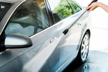 cropped view of car cleaner washing automobile with water pressure outside