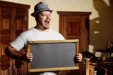 a fat cheerful man in a Bavarian hat with a feather during the celebration of Oktoberfest holds a...