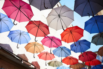 Fototapeta na wymiar colorful umbrellas against the sky between the houses, beautiful umbrellas