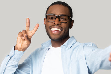 Smiling black man in glasses make selfie on gadget