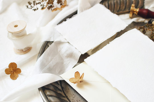 Winter, fall styled wedding, birthday table composition. Stationery mockup scene. Closeup of greeting cards, envelope, dry hydrangea flowers and ribbon on old vintage silver tray. Selective focus.