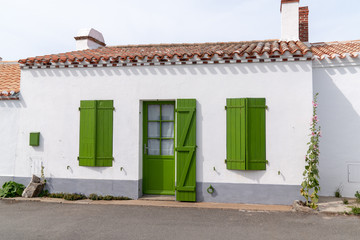 Fototapeta na wymiar White house facade with green shutters blinds and door in Noirmoutier island France
