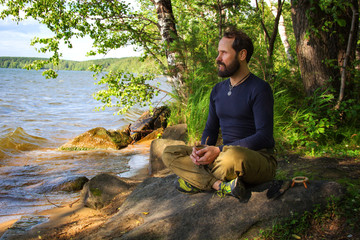A bearded man is meditating by the river Emotional meditating Lifestyle. Introspection Relaxing