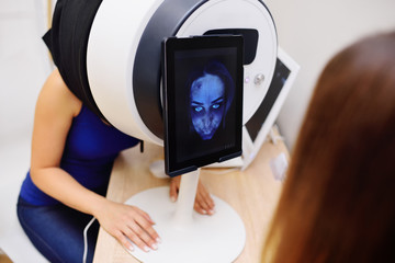 facial skin diagnostics equipment for dermatology and cosmetology. Cosmetologist analyzes the skin...