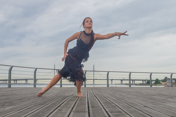 Fototapeta na wymiar the waterfront girl in a black dress dancing