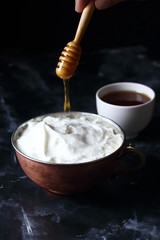 Honey and yogurt in a bowl, pouring honey into honey
