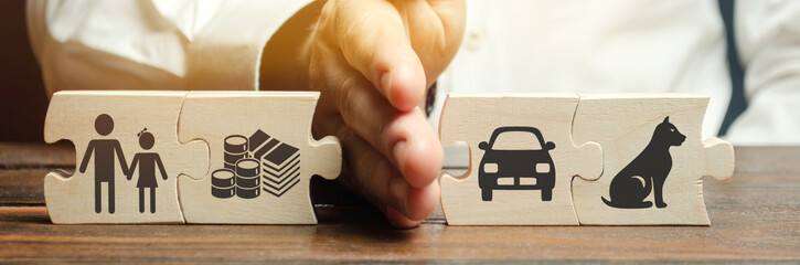 A man shares wooden puzzles with images of property, children and pets. The concept of divorce. The...