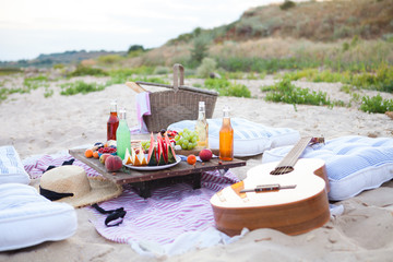 Fototapeta na wymiar Picnic on the beach at sunset in the style boho, food and drink conception