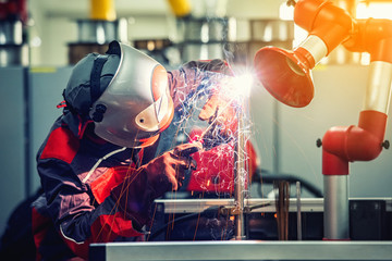 Fototapeta na wymiar Industrial welder worker is welding metal part in factory with protective mask welding metal 