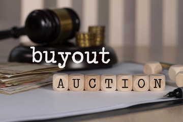 Words BUYOUT AUCTION  composed of wooden dices.